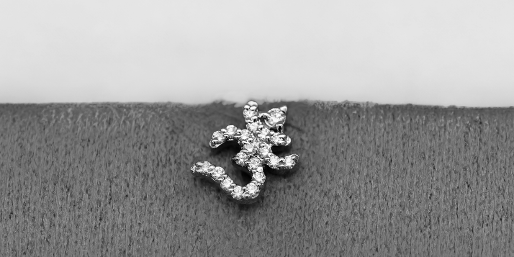 A black and white image of traditional ohm shaped diamond nose pin