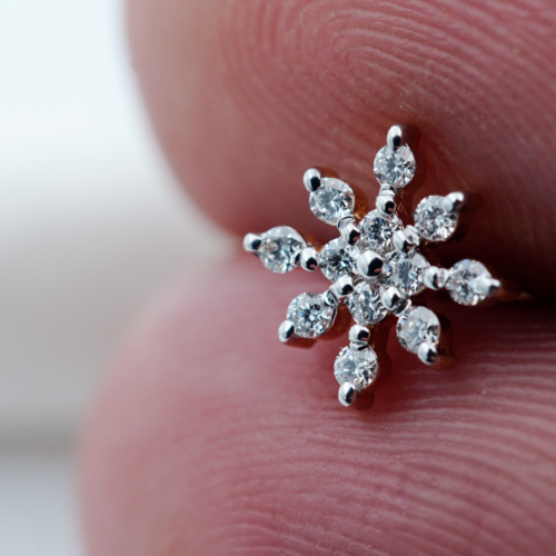 Snowflake designed diamond nose pin for women held in a person's hand