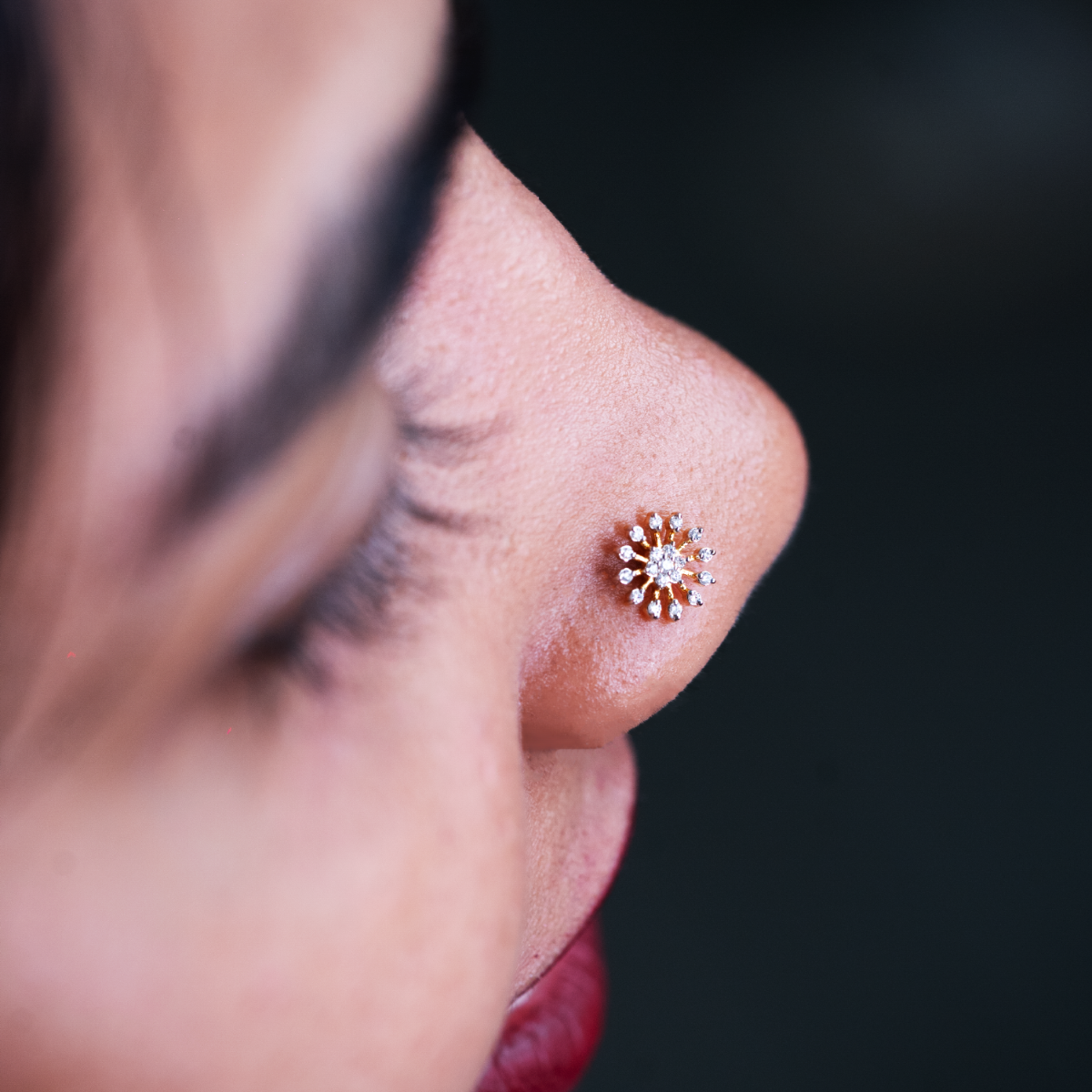 model wearing a nose pin with multiple small diamonds in a sun burst shape.
